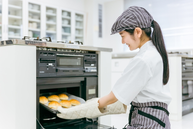 パンをオーブンで焼く女性
